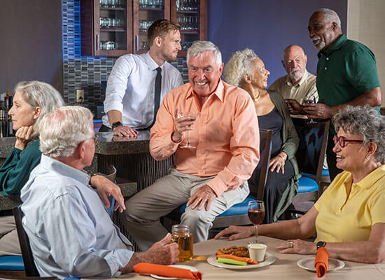 Groups of senior friends gathered around a bar talking and laughing the night away.